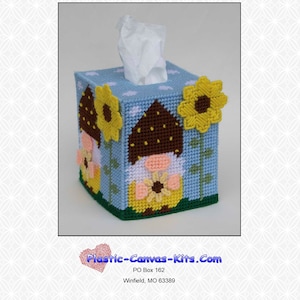 Pode incluir: Uma capa de caixa de lenços de tela plástica azul e amarela com um gnomo e girassóis. O gnomo está usando um chapéu marrom e uma camisa rosa com uma flor amarela. A capa da caixa de lenços é projetada para ser usada com uma caixa de lenços padrão.