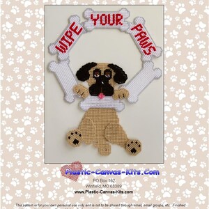 Op de afbeelding: Een plastic canvas-knutselset met een mopshond met de woorden "Wipe Your Paws" in een botvormig frame. De set is ontworpen voor kruissteek en bevat een patroon voor een mopshond met een botvormig frame.