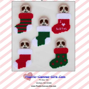 May include: Five plastic canvas kits featuring a sloth wearing a Christmas stocking. The stockings are red and green with white trim. One stocking has the text "I love sloths" on it.
