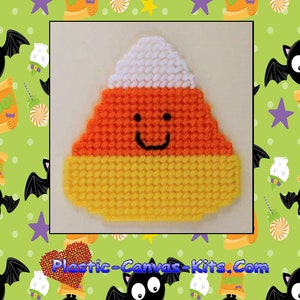May include: A plastic canvas kit for a candy corn magnet. The candy corn is orange, yellow, and white with a smiling face. The kit is labeled "1648 Candy Corn Magnet" and "Plastic-Canvas-Kits.Com".