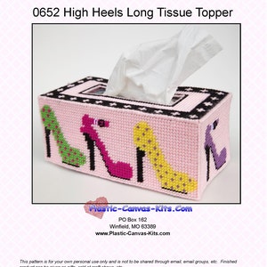 May include: A pink plastic canvas tissue box cover with a black border and a design of four high-heeled shoes in different colors. The shoes are green, pink, yellow, and purple. The text "Plastic-Canvas-Kits.Com" is printed on the bottom of the image.