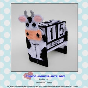 May include: A 3-D plastic canvas kit of a cow with a perpetual calendar. The calendar is made of plastic canvas and has a black and white cow design. The calendar is labeled "1151 Cow 3-D Perpetual Calendar" and "Plastic-Canvas-Kits.Com".