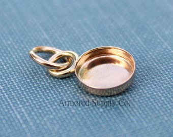 May include: A gold-toned metal pendant with a round, flat, open-back bezel. The pendant has a loop for attaching to a chain or cord.
