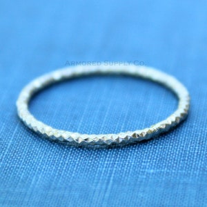 May include: A silver ring with a textured, diamond-shaped pattern.