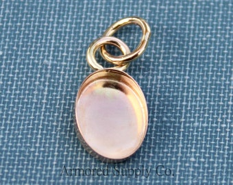 May include: Gold-toned pendant with a round, flat, bezel setting. The pendant has a loop at the top for attaching to a chain or cord.