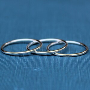 May include: Three silver rings stacked on top of each other on a blue background.