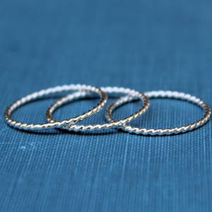 May include: Three silver rings with a twisted design. The rings are stacked on top of each other.