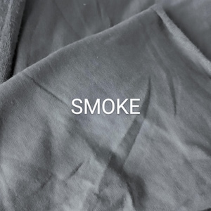 Pu&ograve; includere: Primo piano di un tessuto grigio con la parola "SMOKE" stampata in bianco.