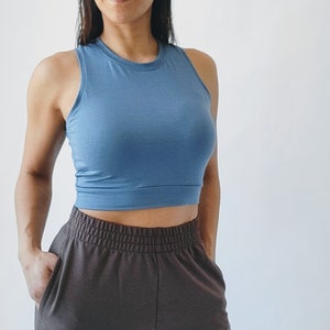 May include: A blue sleeveless crop top with a round neckline. The top is made of a soft, stretchy fabric and has a relaxed fit.