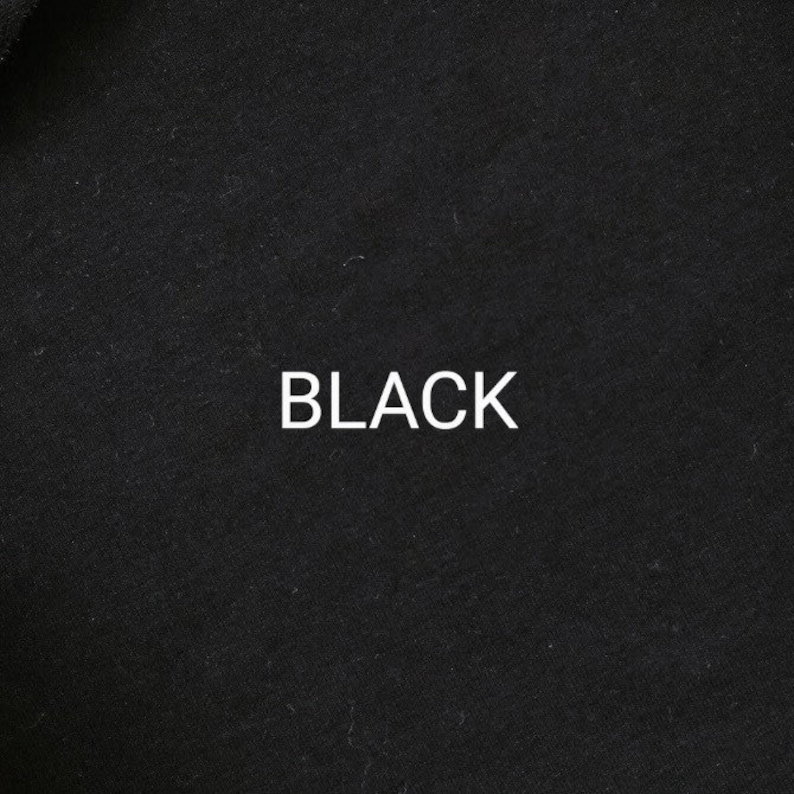 Pu&ograve; includere: Primo piano di un tessuto nero con la parola "BLACK" stampata in bianco.