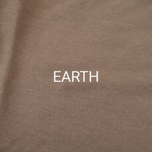 Pu&ograve; includere: Primo piano di un tessuto marrone con una texture sottile. La parola "EARTH" &egrave; stampata in lettere bianche sul tessuto.