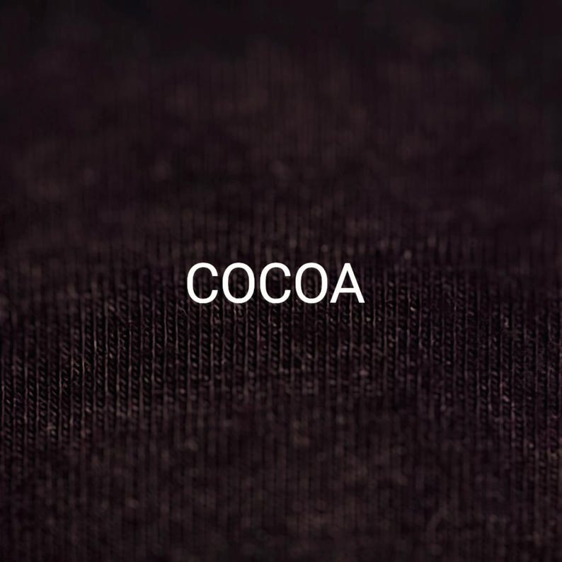 Pu&ograve; includere: Primo piano di un tessuto marrone scuro con la parola "COCOA" stampata in bianco.
