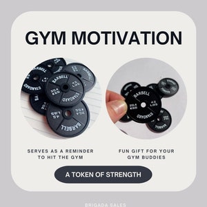 May include: Black weight plates with white text that reads "BARBELL STANDARD 20.4 KGS 45 LBS". The plates are a reminder to hit the gym and a fun gift for gym buddies. A token of strength.