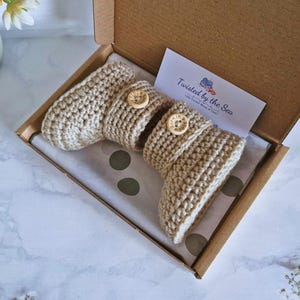 showcasing a pair of parchment coloured booties in a brown postal box ready to be wrapped with a Twisted by the Sea card.