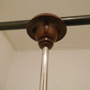 May include: A close-up of a ceiling mounted light fixture with a brown wooden canopy and a silver metal pole.