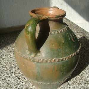 Peut inclure: Une cruche en c&eacute;ramique verte et brune avec une anse et un motif de perles. La cruche porte le num&eacute;ro 1891 sur le c&ocirc;t&eacute;.