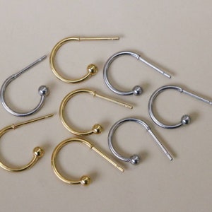May include: Eight hoop earrings with a small ball at the end. Four earrings are gold and four are silver.