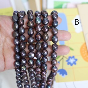May include: A strand of dark gray baroque pearls with iridescent hues. The pearls are strung on a clear thread and are approximately 8-9mm in size.