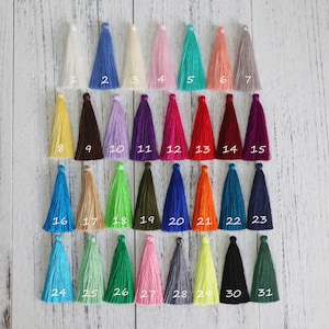 May include: A color chart of 31 different tassel colors. The tassels are arranged in rows and numbered 1 through 31. The colors include white, blue, cream, pink, turquoise, coral, gray, yellow, brown, lavender, purple, red, maroon, teal, beige, green, olive, navy, orange, dark blue, black, and light green.