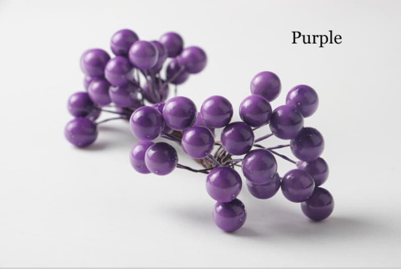 May include: Purple berry sprigs with small round berries. The berries are clustered together on thin wire stems.