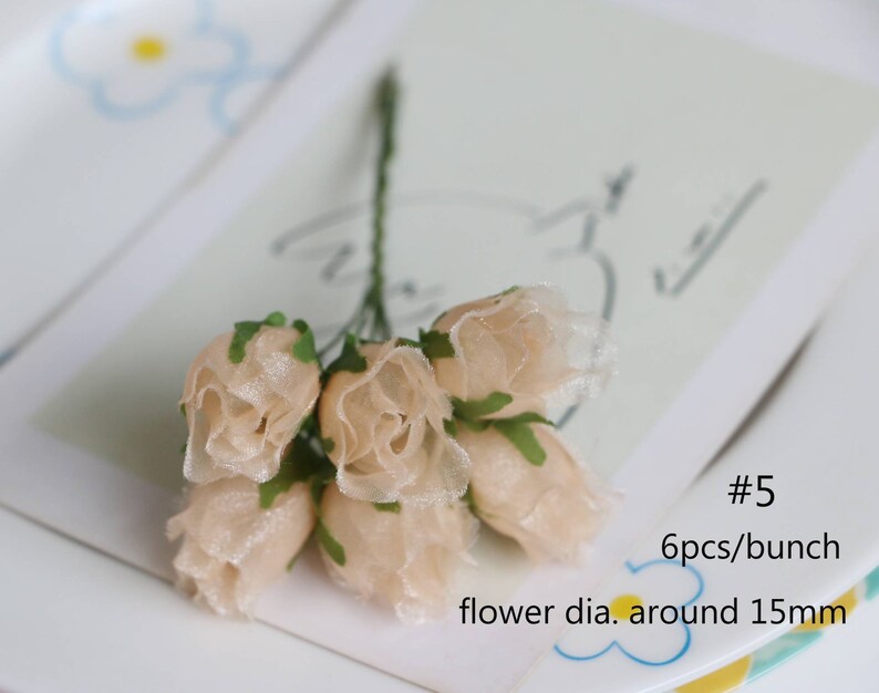 May include: A bunch of six small, beige fabric roses with green leaves. The roses are about 1.5 inches in diameter. #5 6pcs/bunch flower dia. around 15mm