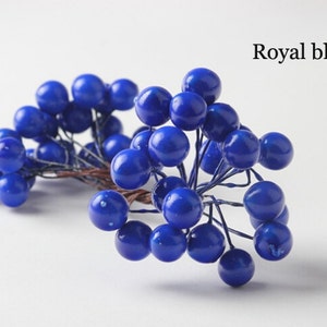 May include: A bunch of royal blue berry sprigs. The berries are clustered together on thin wire stems.