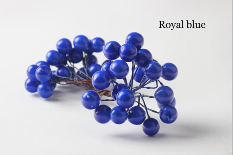 May include: A bunch of royal blue berry sprigs. The berries are clustered together on thin wire stems.