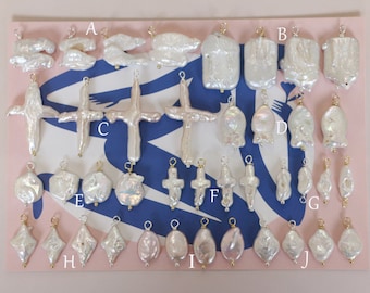 May include: A collection of 20 white and pink pearl pendants with gold accents. The pendants are arranged in rows on a pink and blue background with letters A through J labeling each row.