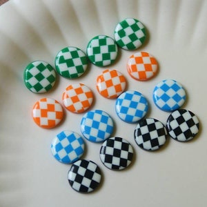 May include: Assortment of round, checkered buttons in various colors, including black and white, green and white, blue and white, and orange and white.