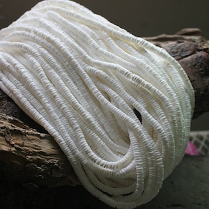 May include: A strand of white shell beads, made from natural materials, perfect for jewelry making or crafting.