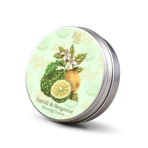May include: A silver tin with a green and white label featuring a botanical illustration of bergamot and neroli flowers. The label reads "Neroli & Bergamot Shaving Cream".