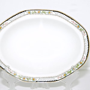 Może przedstawiać: Biała owalna półmisek do serwowania z czarną i złotą obwódką i kwiatowym wzorem w odcieniach czerwieni, żółci, zieleni i błękitu.