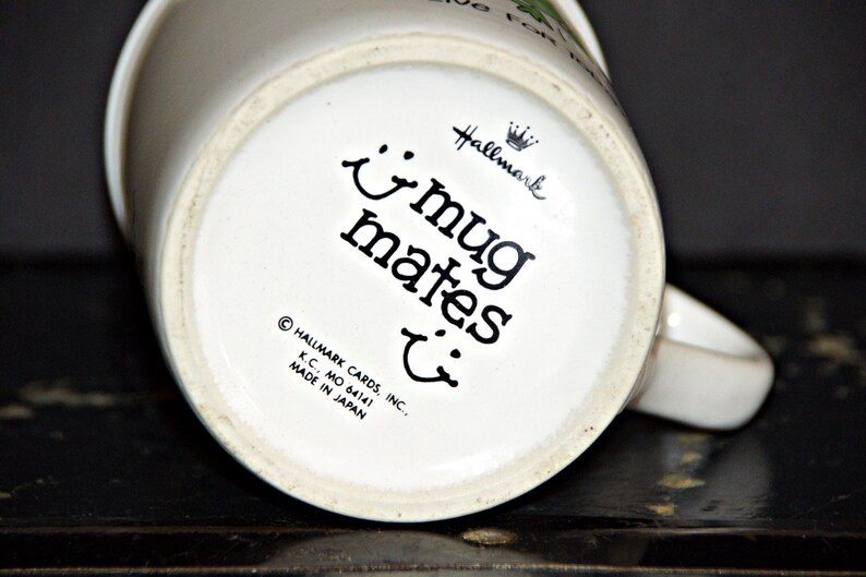 May include: White ceramic mug with a black and white design that says "mug mates" with a crown and the word "Hallmark" on the bottom. The mug is made in Japan.