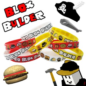 Op de afbeelding: Een set van zes kleurrijke siliconen armbanden met de tekst "Pro Blox Builder" erop gedrukt. De armbanden bevatten verschillende afbeeldingen, waaronder een pizzapunt, een donut, een hamburger en een hoed. De afbeelding bevat ook een piratenhoed, een zilveren gereedschap, een gele hamer en een cartoonfiguur met een gele helm.