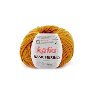 Peut inclure: Un pelote de laine Katia Basic Merino de couleur orange vif. L'étiquette indique "Katia Basic Merino pure laine mérinos superwash".