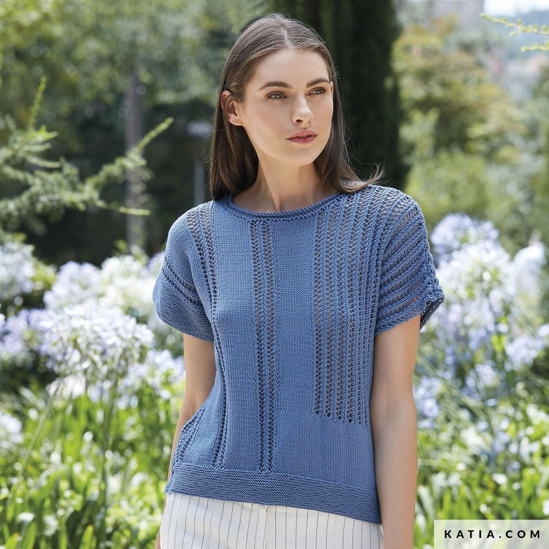 May include: A light blue knitted top with a delicate openwork pattern. The top has short sleeves and a round neckline.