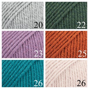 K&ouml;nnte beinhalten: Eine Sammlung von Garnkn&auml;uel in verschiedenen Farben, darunter Grau, Gr&uuml;n, Lila, Orange, T&uuml;rkis und Rosa. Die Kn&auml;uel sind mit den Nummern 20, 22, 23, 25, 26 und 26 gekennzeichnet.