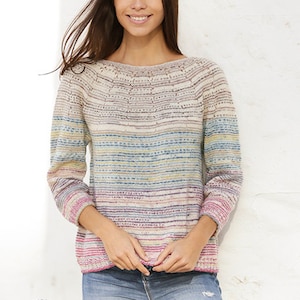 Puede incluir: Un su&eacute;ter a rayas con un patr&oacute;n horizontal colorido en tonos de rosa, azul, amarillo y verde. El su&eacute;ter tiene cuello de barco y mangas largas. La modelo lleva pantalones vaqueros azules y sonr&iacute;e. La imagen incluye el texto "DROPS DESIGN" y "www.garnstudio.com".