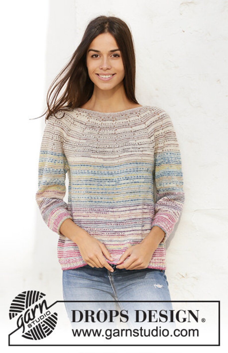 Puede incluir: Un su&eacute;ter a rayas con un patr&oacute;n horizontal colorido en tonos de rosa, azul, amarillo y verde. El su&eacute;ter tiene cuello de barco y mangas largas. La modelo lleva pantalones vaqueros azules y sonr&iacute;e. La imagen incluye el texto "DROPS DESIGN" y "www.garnstudio.com".
