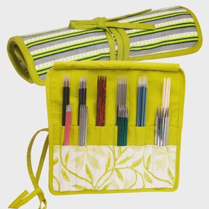 Könnte beinhalten: Eine lindgrüne Stricknadelrolle mit einer Vielzahl von Nadeln in verschiedenen Farben und Materialien. Die Rolle besteht aus einem gestreiften Stoff in Grau-, Grün- und Weißtönen. Der Innenraum ist lindgrün mit Taschen und einem floralen Muster.