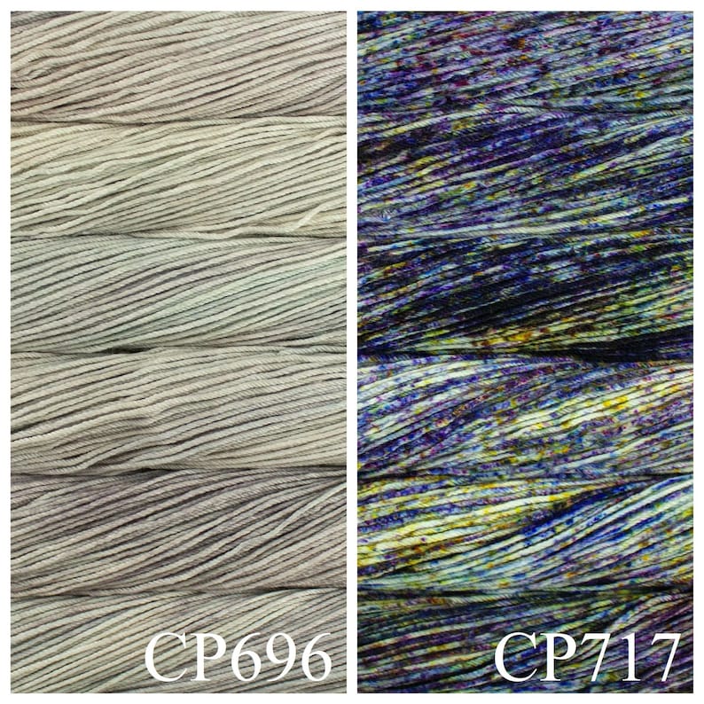 May include: Two skeins of yarn, one in a light grey colour with subtle green and purple hues, and the other in a dark blue colour with purple, green, and yellow speckles. The skeins are labelled "CP696" and "CP717".