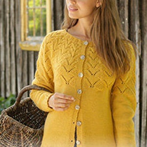 K&ouml;nnte beinhalten: Ein gelber Cardigan mit Knopfleiste und einem zarten Spitzenmuster. Der Cardigan wird von einer Frau mit langen braunen Haaren getragen.