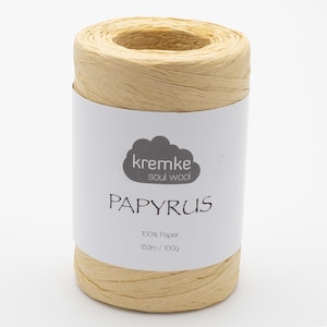 May include: A cylindrical spool of natural-colored Papyrus paper yarn. The label reads "kremke soul wool" and "PAPYRUS", with details about the paper content and weight. The yarn is 100% paper, 153m / 100g.