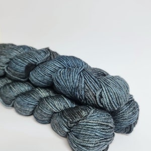 May include: Two skeins of dark blue yarn with a subtle colour variation. The yarn is soft and fluffy, perfect for knitting or crocheting.