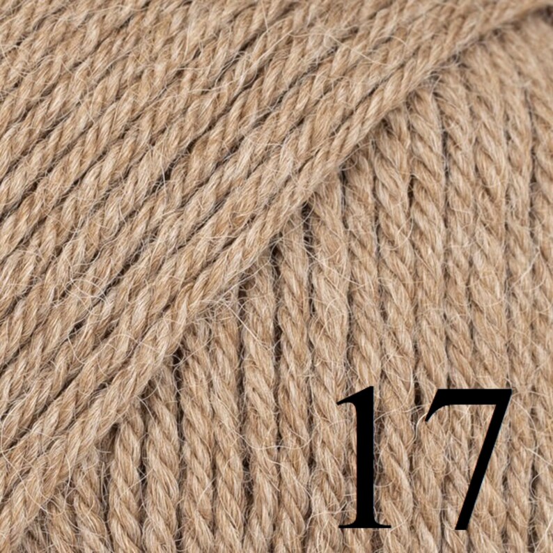 May include: Close-up of a ball of light brown yarn. The yarn is tightly twisted, showing a textured surface. The number "17" is printed in black on the yarn. Ideal for knitting and crochet projects.