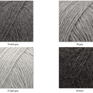 May include: Four skeins of yarn in various shades of gray and black. The colors are labeled: dark grey, grey, light grey, and black. The yarn is tightly wound and appears soft, suitable for knitting or crocheting projects.