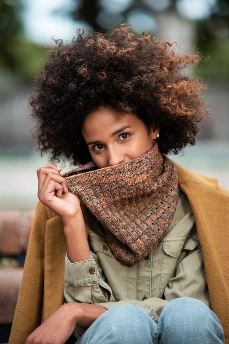 May include: A person wearing a brown and green knitted scarf with a brown jacket and a green shirt.