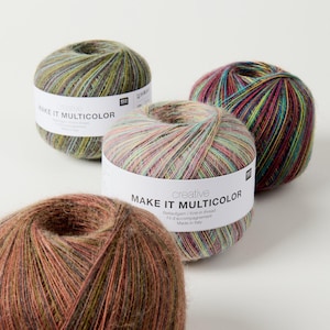 Peut inclure: Quatre pelotes de laine rondes à la texture duveteuse, chacune entourée d'une étiquette en papier blanc portant l'inscription "creative MAKE IT MULTICOLOR". Les fils présentent des mélanges variés de vert, marron, rose et bleu foncé.