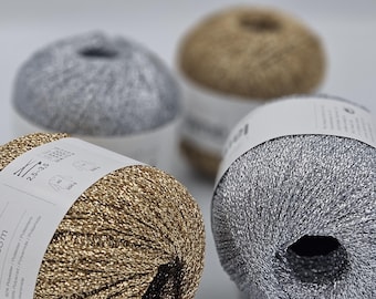 May include: Four balls of yarn in gold, silver, and two shades of grey. The yarn is sparkly and has a metallic sheen. The yarn is labelled "2.5-3.5 mm" and "50g".
