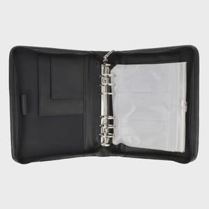Peut inclure: Un classeur noir zippé ouvert avec un mécanisme à anneaux en métal argenté. L'intérieur comprend des poches et une pochette en plastique transparent pour ranger des documents ou des photos. Le classeur est ouvert, affichant son contenu.